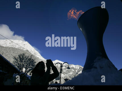 A tourist takes a picture of a replica of the Olympic Flame in Cesana near Turin, Italy, Monday, 20 February 2006. After a snow storm on late Sunday, the weather in the Olympic mountain region around Sestriere and San Sicario is nice and sunny at temperatures from four to nine centigrades below zero. Photo: Bernd Thissen Stock Photo