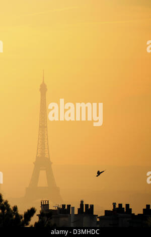 Eiffel Tower viewed from Montmartre on sunset. Dark silhouette of the tower and Parisian roofs against the naturally red sky. Stock Photo