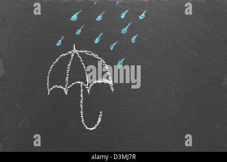 Chalk drawing of an umbrella and rain drops on slate Stock Photo