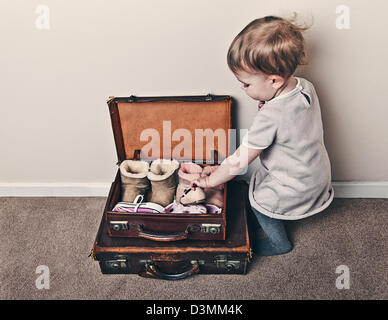 Baby Girl Packing Shoes into Case Stock Photo