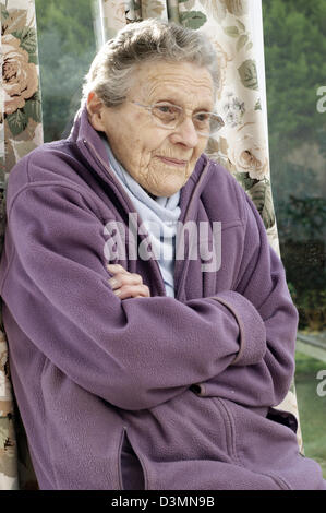 Elderly woman wearing a fleece jacket & a warm scarf trying to keep warm in cold conditions Stock Photo