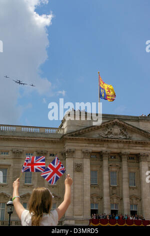 Battle of Britain Memorial Flight passing over Buckingham Palace London - young girl shows patriotism - Queen watches from balcony. British flags Stock Photo