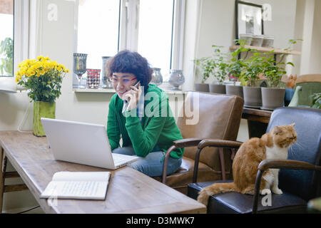 Young Chinese Woman Shopping Online while Talking on Mobile Phone Stock Photo