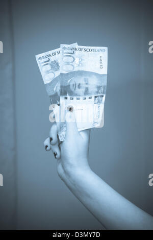 Girls hand holding two £100 Scottish bank notes Stock Photo