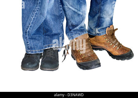 Two pairs of male and female legs in jeans with boots attached to each other laces - love forever Stock Photo