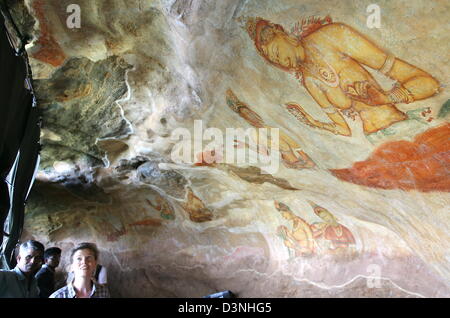 Visitors are amazed by the fresco Cloud Maidens on the rock fortress Sigiryia on Sri Lanka, 27 April 2006. Sigiriya is a 120 metres monolith circa 90 kilometres north of the Holy City Kandy with ruins of a king's fortress dating ennd of fifth century. The frescoes derriving from the same time picture a group of heavenly mymphs (Apsaras) with flowers. Ruin city Sigiriya was listed U Stock Photo