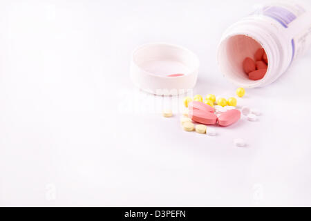 Medicine and pills pouring out of the white bottle scattered around Stock Photo