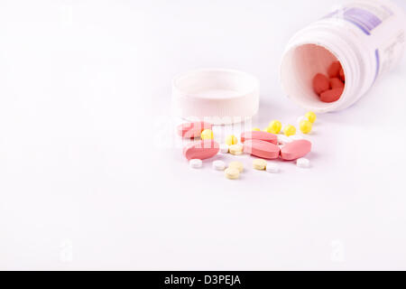 Medicine and pills pouring out of the white bottle scattered around Stock Photo