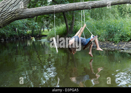 9 year old girl swinging above creek Stock Photo