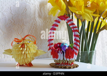 origami easter chick, origami basket with mini Easter eggs and daffodils in the background Stock Photo