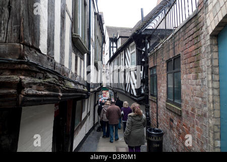 People walking along very narrow medieval passage with timber framed buildings on either side in Grope Lane Shrewsbury KATHY DEWITT Stock Photo