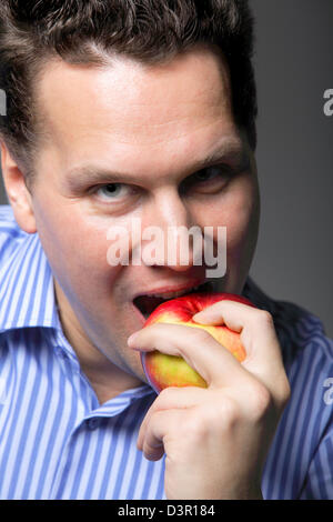Portrait of a mature man about to eat a red apple gray background Stock Photo