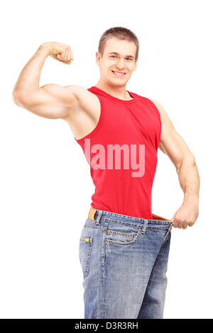 Weight loss man in an old pair of jeans showing his muscular body isolated on white background Stock Photo