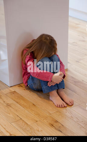 Young girl sat unhappy on the floor Stock Photo