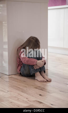 Young girl sat unhappy on the floor Stock Photo