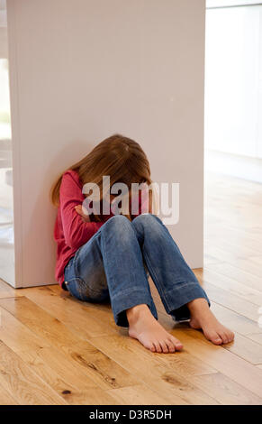 Young girl sat unhappy on the floor Stock Photo