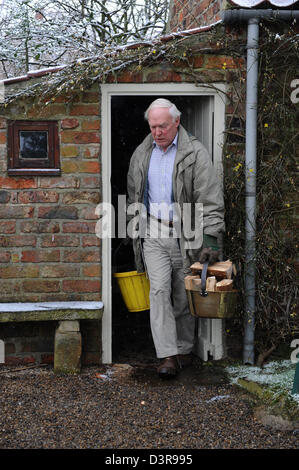 Pensioner carrying logs from log shed at home in north yorkshire uk Stock Photo