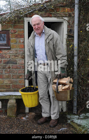 Pensioner carrying logs from log shed at home in north yorkshire uk Stock Photo