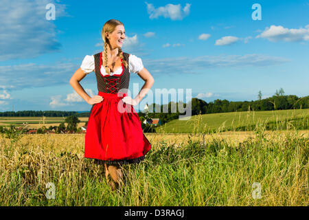 Young Bavarian woman on meadow wearing dirndl and smiling Stock Photo