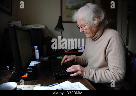 Elderly english lady sitting in office at home learning how to use a computer. Stock Photo