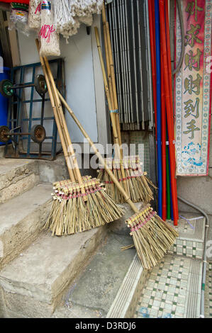 Handmade brooms sit on the steps outside a shop in Hong Kong Stock Photo