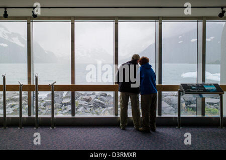 Tourist looks out large windows, Boggs Visitor Center, Portage Lake, Portage Glacier, Chugach National Forest, Portage, Alaska Stock Photo