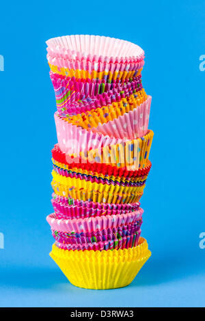 Tall stack of colorful muffin or cupcake cups on blue background Stock Photo