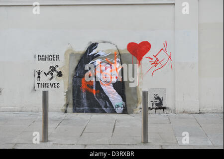 Wood Green, London, UK. 24th February 2013. The collected Graffiti on and near the space where Banksy's Slave Labour picture was. A new picture has appeared on the space where Banksy's 'Slave Labour' graffiti was on the side of Poundland in Wood Green. The picture of a nun pasted to the wall has already been partially ripped with a piece discarded nearby. A small figure of a man has also been painted onto the perspex covering the rat 'Why' picture.Credit: Matthew Chattle/Alamy Live News Stock Photo