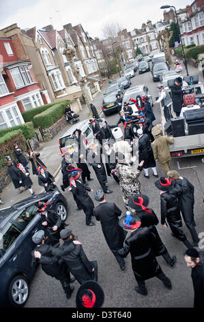 London, UK - 24 February 2013: dressed in fancy dress men from the Orthodox Jewish community of Stamford Hill dance and sing in the streets at the sound of very loud Yiddish music. They are visiting wealthy businessmen and collecting money during the celebrations of Purim 2013. Stock Photo