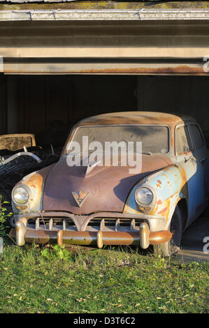 Car from the 1950's sitting rusty and abandoned in an old garage, a1952 Studebaker in evening sunlight. Stock Photo