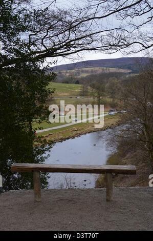 Wooden Bench Overlooking The River Wharfe & Car Park at Bolton Abbey From Dales Way  Long Distance Footpath Wharfedale Yorkshire Stock Photo