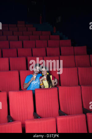Couple enjoying soft drinks while watching movie in a cinema hall Stock Photo
