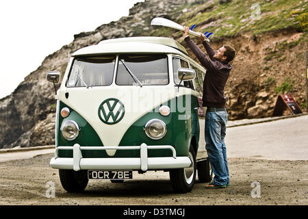 Surfer lifting board from green VW campervan, St Agnes, Cornwall, UK Stock Photo