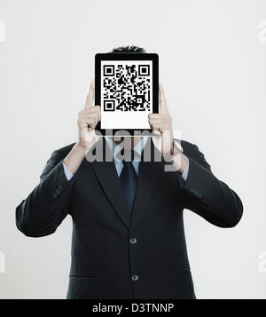 Businessman holding a digital tablet in front of his face with 2D barcode on it Stock Photo