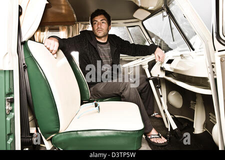 Surfer sits in split screen campervan, St Agnes, Cornwall, UK Stock Photo