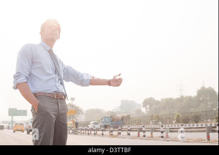 Businessman hitchhiking, Gurgaon, Haryana, India Stock Photo