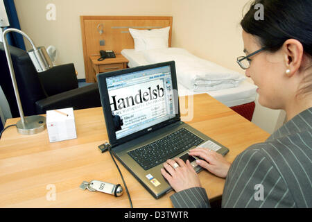 A young woman reads the newspaper 'Handelsblatt' in the Internet in the business Hotel Gates in Berlin, Germany, Wednesday, 13 June 2006. Guests of the hotel have access to the free newspaper offering of 'Pressdisplay' in every room. 250 newspapers from 55 countries in 35 languages can be read online, sometimes even before print. Photo: Gero Breloer Stock Photo