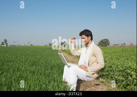 Farmer using a laptop in the field, Sonipat, Haryana, India Stock Photo