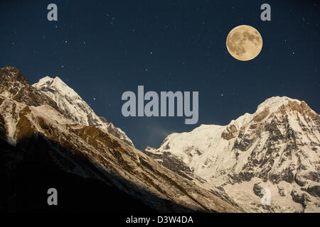 The night sky over Annapurna South in the Annapurna Sanctuary, Himalayas, Nepal, with a full moon. Stock Photo