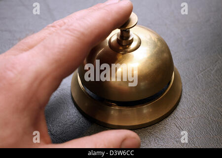A hand presses the brass bell at a hotel reception in Frankfurt Main, Germany, 26 October 2006. Photo: Heiko Wolfraum Stock Photo