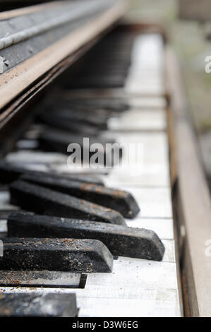 Piano keyboard close up sitting abandoned grunged and broken keyboard sitting outside in the weather, side view shallow DOF. Stock Photo