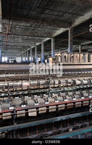 Textile mill weaving machinery sits stopped in an empty closed and abandoned American factory. Stock Photo