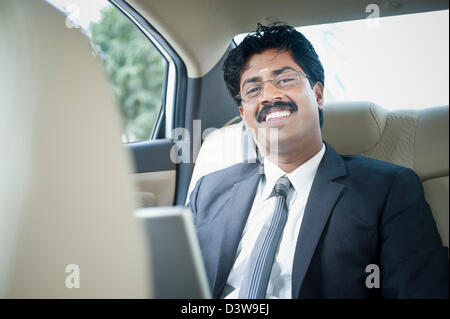 South Indian businessman using a laptop in the car Stock Photo