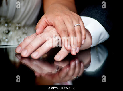 A couples hands lay on top of each other showing off their new wedding rings following the marriage ceremony in England, UK Stock Photo