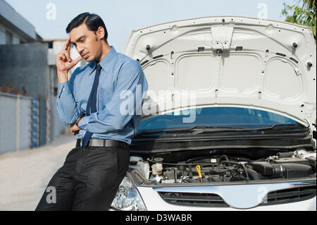 Bengali businessman standing near a broken down car Stock Photo