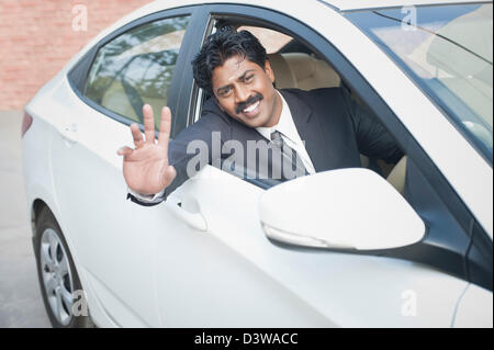 South Indian businessman driving the car and waving hand Stock Photo