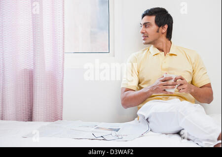 Bengali man having coffee and looking through a window Stock Photo