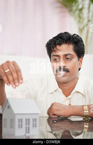 South Indian man holding a model of dream home and smiling Stock Photo ...