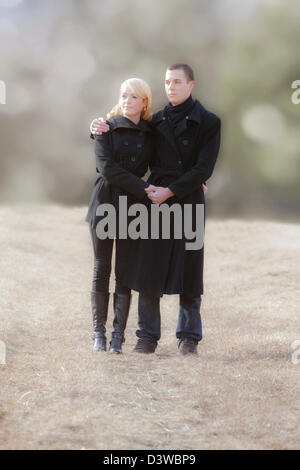 a couple in black clothes is walking in a meadow Stock Photo