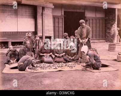 Picking cotton - several people of all ages sitting on mats in a courtyard separating cotton from the plant, circa 1890 Stock Photo